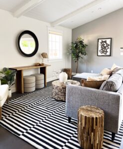 living room staging featuring a monochromatic rug, a love seat with a wooden table next to it and on the opposite wall a mirror, sideboard with two little trendy stools pushed under it. Pure Lux Staging & Design in Burlingame ca