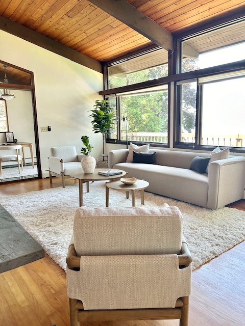 Coastal-modern staged living room with vaulted wood ceiling and large windows at 119 Mussel Bed Shoal Rd, Portsmouth RI