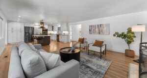 Open-concept living room and kitchen in a staged West Linn, Oregon home with modern furnishings and warm accents.